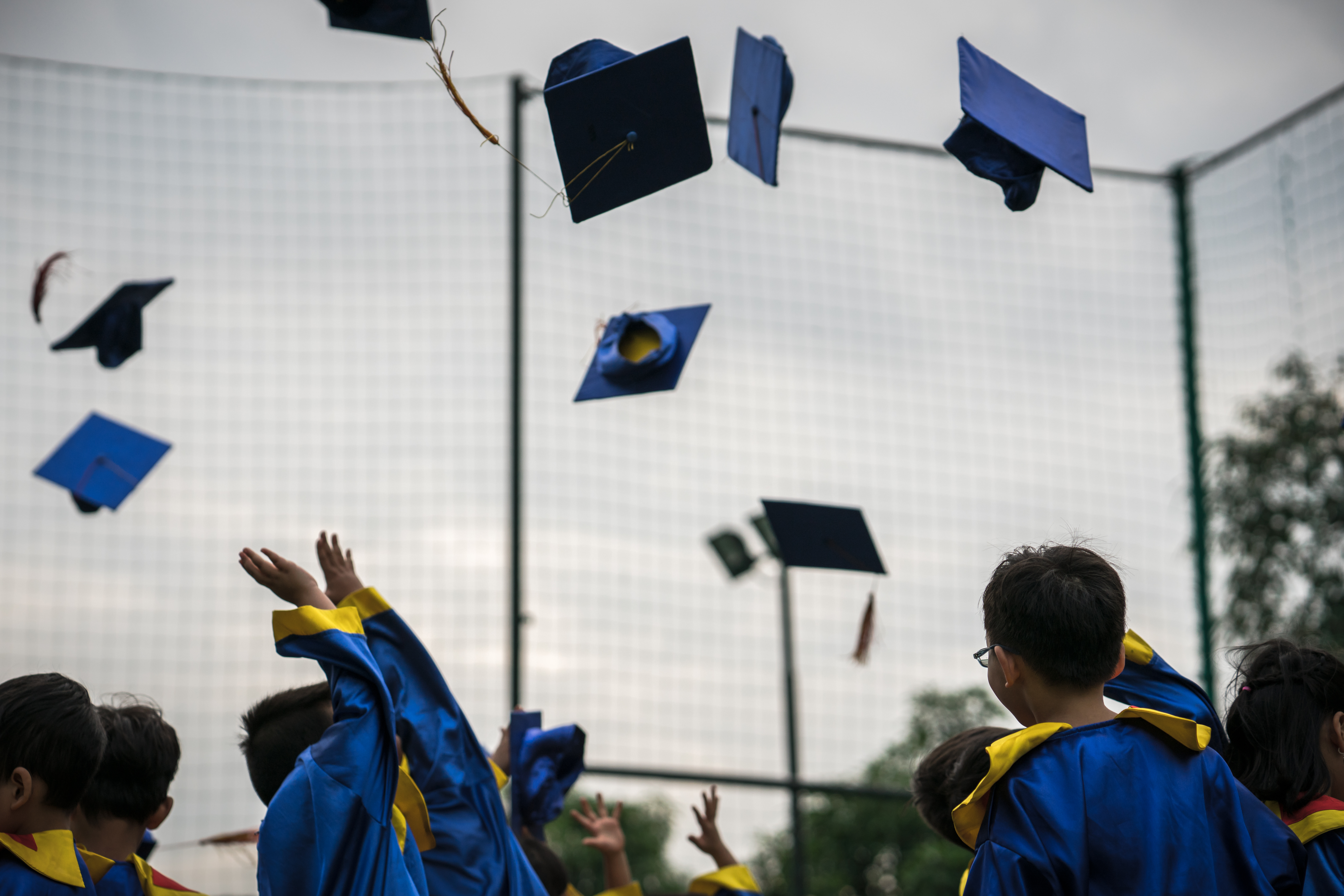 Image of children throwing graduation caps in the air